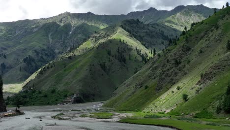 A-drone-pans-out-to-frame-a-raft-floating-in-Naran’s-waters-against-a-dramatic-mountainous-landscape,-blending-adventure-with-nature