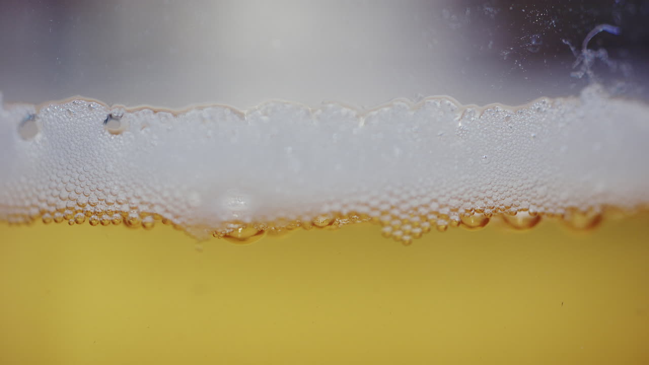 Primo piano ravvicinato di schiuma di birra e bollicine che si formano sulla superficie di una bevanda.