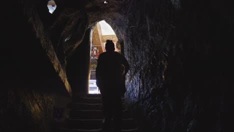 Shot-of-a-woman-climbing-stairs-in-a-dark-corridor-towards-a-light-source,-captured-in-a-Buddhist-hell-reenactment-at-Linh-Phuoc-Pagoda-in-Da-Lat,-Vietnam