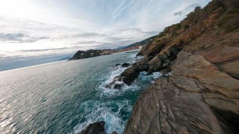 A-scenic-rocky-coastline-with-waves-crashing-against-the-shore-at-sunset,-aerial-view