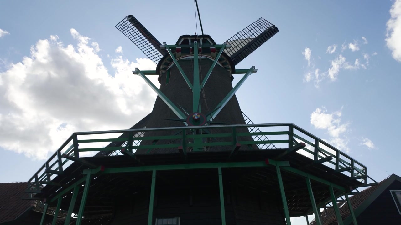 Kincir angin ikonik berputar di bawah langit biru di desa Zaanse Schans, pedesaan tradisional Belanda.