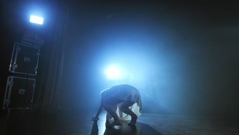 Una-Bailarina-Moderna-Con-Un-Vestido-Corto-Blanco-Realiza-Hermosas-Danzas-Dramáticas-De-Plástico-Corriendo-Por-El-Escenario,-Cayendo-Al-Suelo-Y-Girando.-Linternas-Y-Humo.