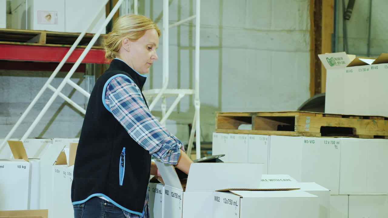 una mujer con una tableta tiene inventario en un almacén