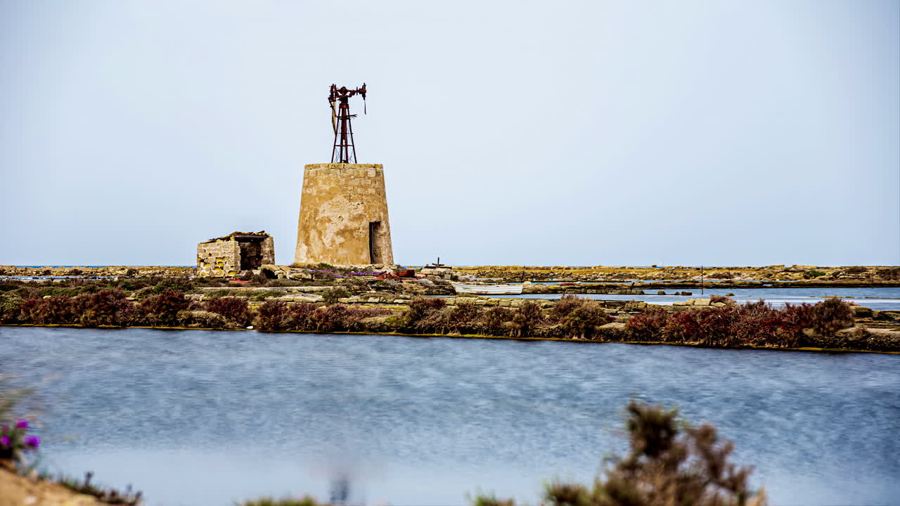 낮에 이탈리아 시칠리아 토레 누비아에 있는 햇볕에 쬐인 소금 증발 연못의 정적 전망