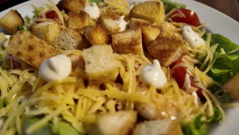 close-up view of a caesar salad with croutons, dressing, and shredded cheese