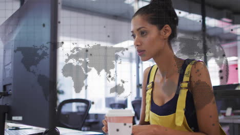 animation of world map, globe and data over biracial casual businesswoman using computer at office