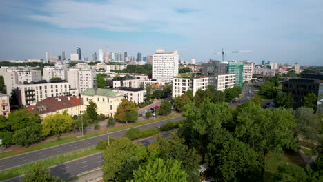 Toma-Aérea-Inclinada-Hacia-Abajo-Que-Muestra-Automóviles-En-La-Autopista-En-El-área-Suburbana-De-Varsovia-Y-El-Horizonte-Del-Centro-En-Segundo-Plano