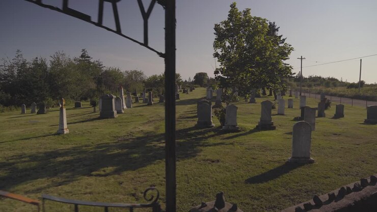 Il cimitero in cima alla collina. Un vecchio cimitero sull'isola di Brier, Nuova Scozia, in una giornata di sole nel tardo pomeriggio. Lenta panoramica a piedi attraverso le lapidi e la parte anteriore del cancello arrugginito