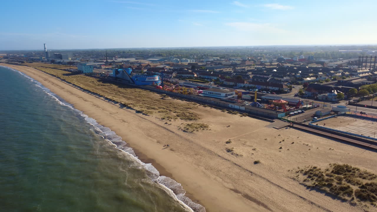 Great Yarmouth Wellington Pier and beach low circling aerial drone shot, Norfolk coast. This is a traditional British seaside town with amusement attractions and arcades