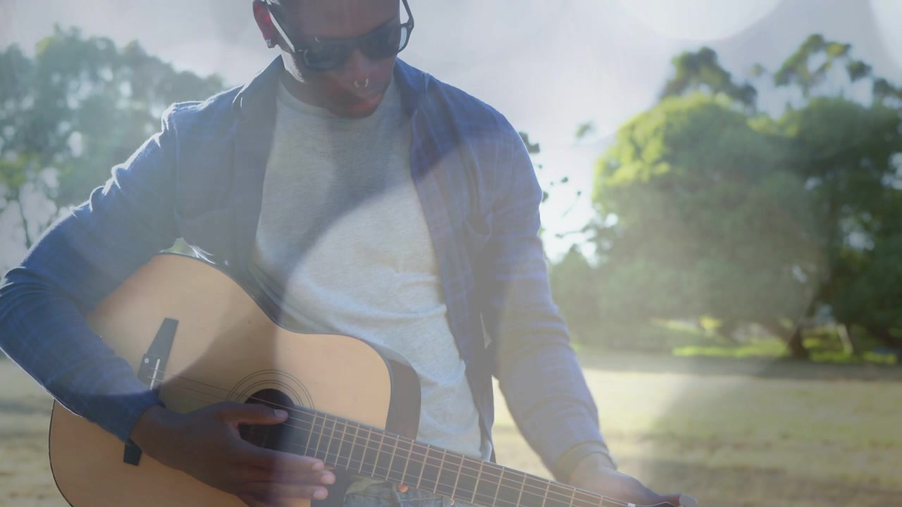 Músico afinando, depois dedilhando e tocando violão acústico para videoclipe, com reflexos solares