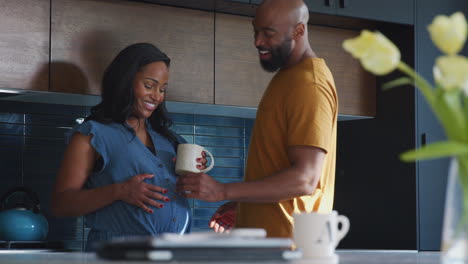 Loving-Hispanic-Husband-With-Pregnant-Wife-At-Home-In-Kitchen-Together