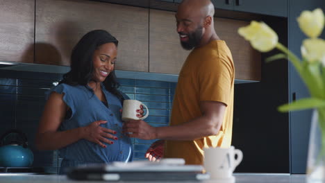 loving hispanic husband with pregnant wife at home in kitchen together