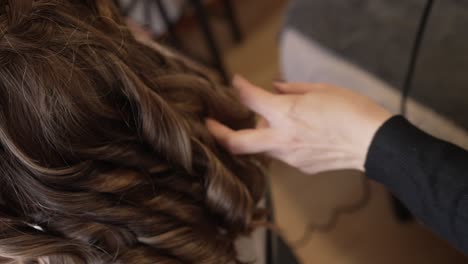 close up of curling iron styling shiny brown hair strands