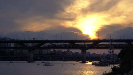 subway train silhouette moving over han river at cheongdam bridge when golden sun goes down to the horizon at sunset seoul