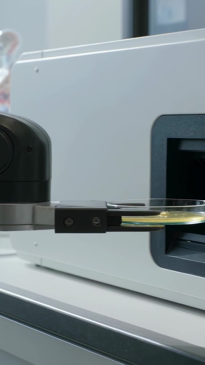 Vertical video: Reacting to analyzer prompt, robot placing petri plate into slot in lab for test