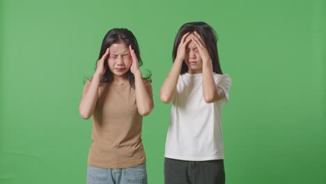 young asian women victims of violence with bruise on bodies stressing and having a headache on green screen background in the studio