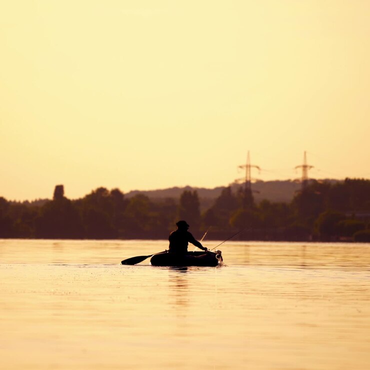 Man fishing from a boat at sunset