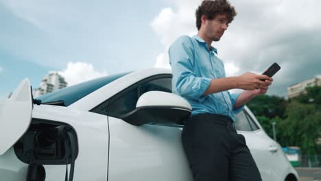 Suit-clad-businessman-with-progressive-ambition-leaning-on-his-electric-vehicle.