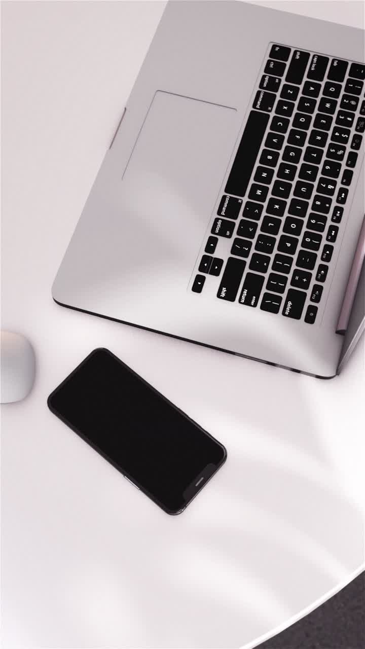 Laptop e smartphone su scrivania bianca con ombre in movimento