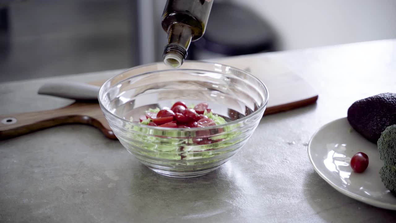 disparo de primer plano de verter aceite de oliva en un tazón con ensalada fresca