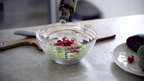 Closeup shot of pouring olive oil in bowl with fresh salad