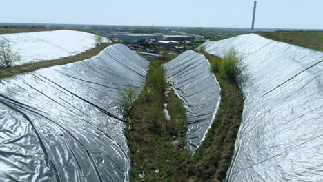 aerial view of the sides of garbage dump hill covered with protective film