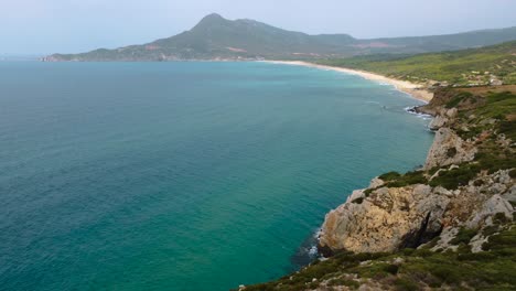 Szenische-Natürliche-Felsige-Küstenstrand-sandbucht-Auf-Der-Touristischen-Ferieninsel-Sardinien,-Italien,-Mit-Bergen-Und-Sonne,-Klarem-Blauem-Türkis-Und-Ruhigem-Wasser-In-Der-Nähe-Von-Costa-Rei