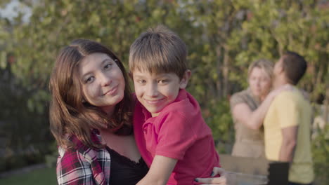 Happy-teenage-girl-standing-with-her-preteen-brother-in-arms