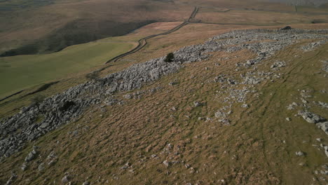 flying high over rocky moorland and hiker in english countryside at ingleton yorkshire uk