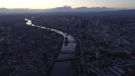 AERIAL:-Establishing-Shot-above-all-of-Frankfurt-am-Main,-Germany-Skyline-high-in-the-Air-at-Dusk-Sunset-light-with-European-Central-Bank-and-Downtown-City-Lights