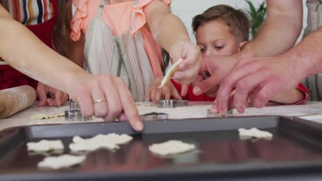 Hands-of-happy-caucasian-family-baking-together,-preparing-cookies-in-kitchen