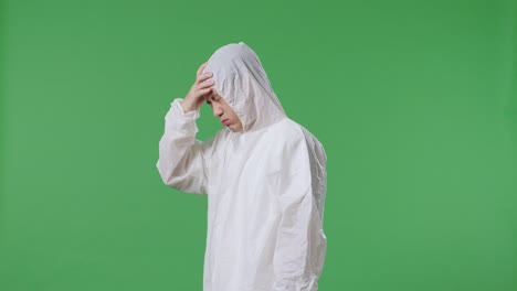 vista lateral de un científico masculino asiático con dolor de cabeza mientras está de pie en el fondo de la pantalla verde