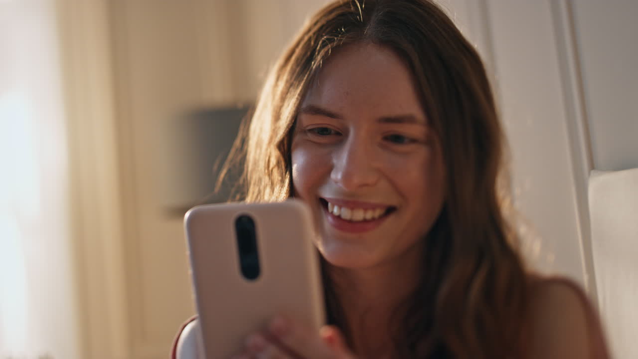 mujer feliz llamando en video a la luz del sol dorada en primer plano. niña sonriente agitando el móvil