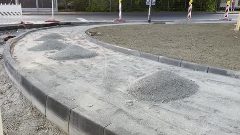 Street-sidewalk-is-being-built-with-small-piles-of-stones-and-path-border-with-construction-site