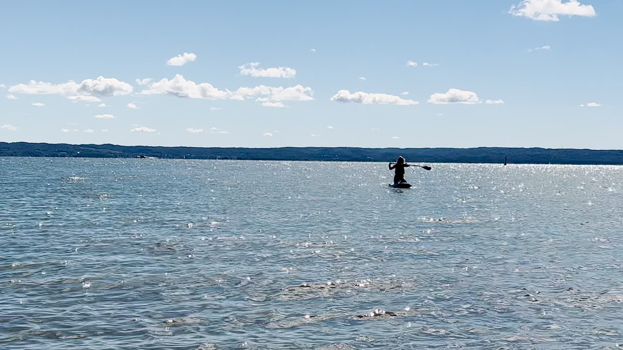 mujer remando en el agua mientras se arrodilla en la tabla de surf en verano