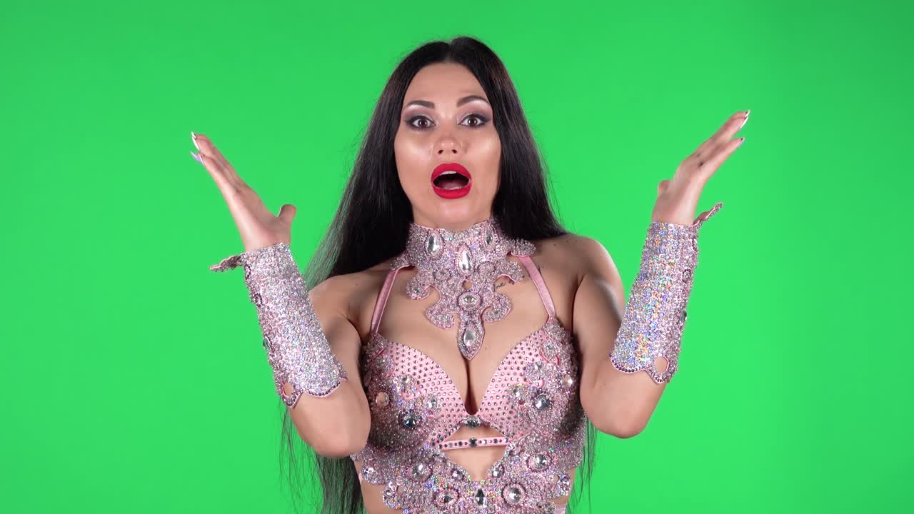 동양의 춤을 위해 멋진 드레스를 입은 아름다운 여성의 초상화 돌과 rhinestones는 충격과 놀란 와우 표정으로 똑바로보고, 그가 본 것에 대해 화를 내고 있습니다.