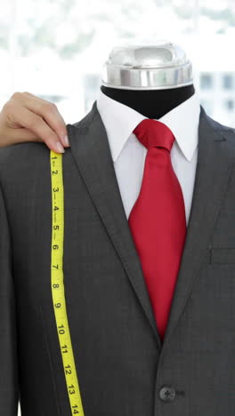 diseñador de moda sonriente midiendo el traje en el maniquí