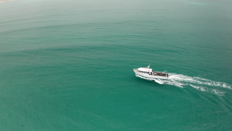 Aerial-view-of-a-ferry-driving-on-the-coast-of-the-Seal-island,-cloudy-day,-in-Australia---tracking,-drone-shot