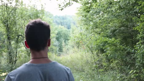 man walking in the green forest - shot from behind