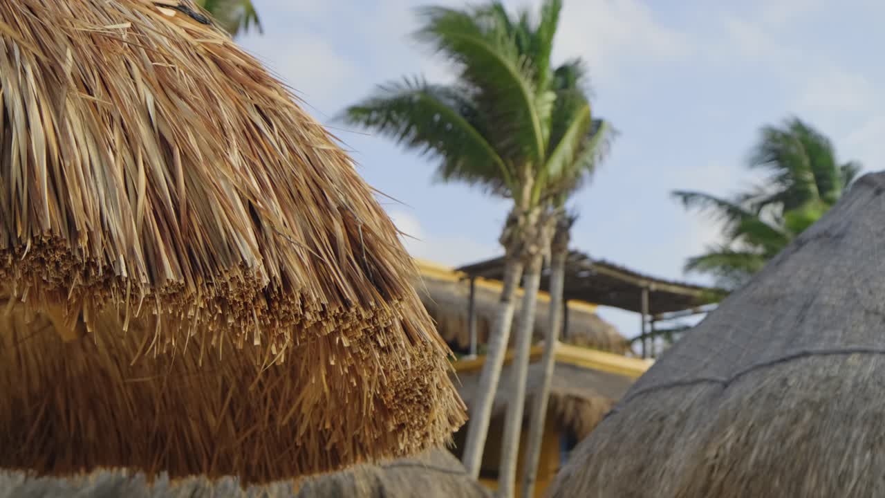 cabañas tiki y tumbonas en la playa de un hotel en un día ventoso