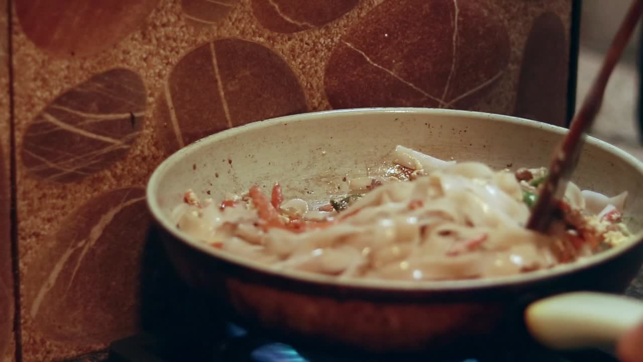 Close up to stir frying flat rice noodles in a simple ho fun or ho fan recipe which is a chinese filipino fusion local dish