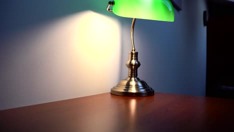 green reading lamp on an empty, brown desk