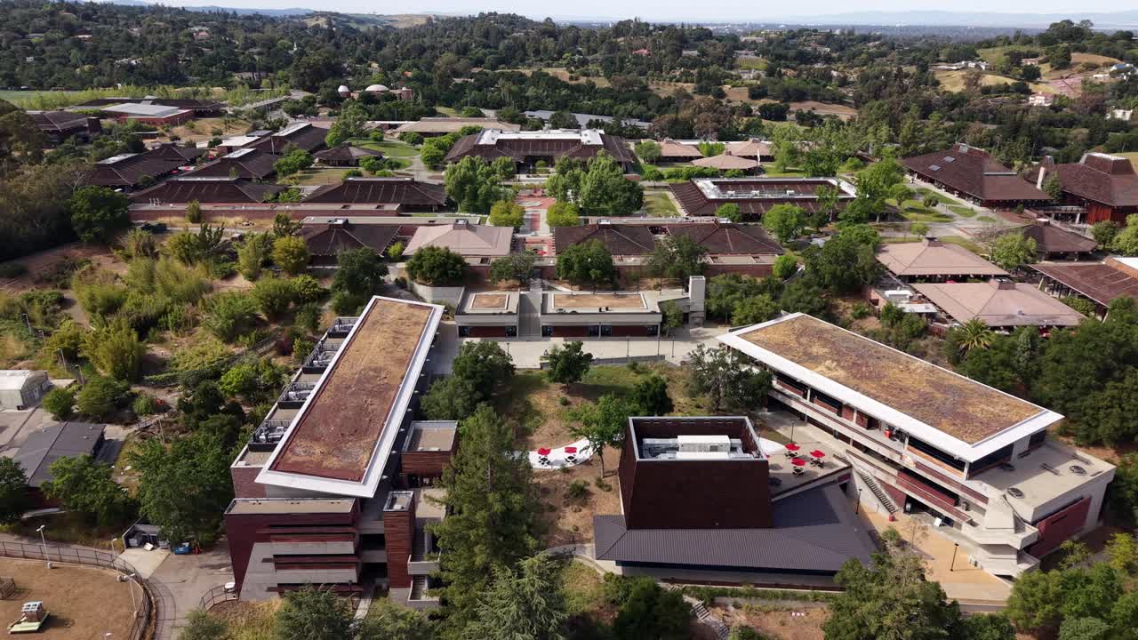 Vista aerea panoramica del campus del Foothill College, un punto di riferimento architettonico, immerso nel lussureggiante paesaggio verde delle colline di Los Altos nella Silicon Valley, California, durante il pomeriggio.