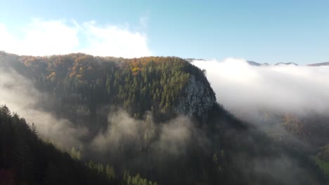 Kiefern,-Die-Eine-Klippe-Durch-Die-Wolken-Bedecken,-Atemberaubende-Aussicht-Auf-Herbstfarben-In-Der-Nähe-Immergrüner-Bäume,-Aufnahme-Aus-Großer-Höhe