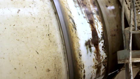 close-up of a rotating cement mixer drum covered in dried concrete and grime, with visible wear from construction site use. industrial, raw and mechanical texture.