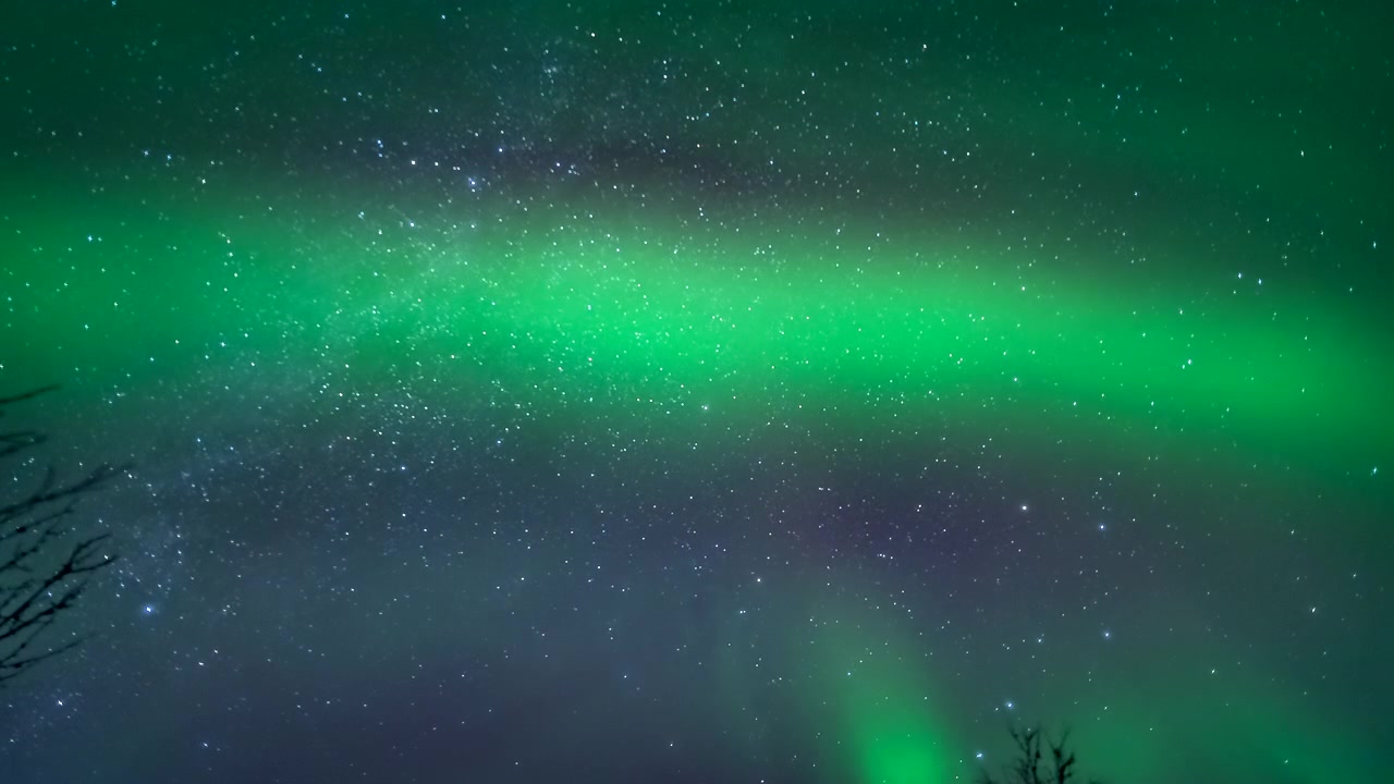 Aurore boreali sfocate appaiono con un bagliore verde che danza nel cielo notturno sopra la Finlandia, mentre stelle e Via Lattea ruotano sopra
