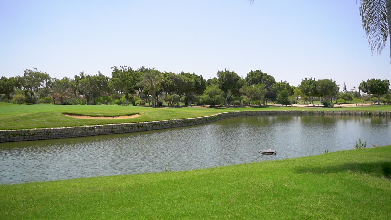 un hermoso campo de golf con césped verde, árboles, lago y césped de plumas en un día soleado