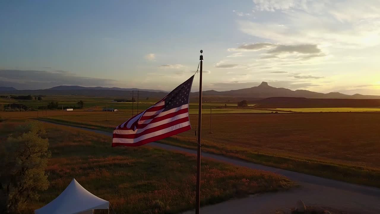 American flag waves over rural landscape