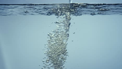 water stream falls on smooth clean surface creating air bubbles water stream falls on smooth clean surface creating air bubbles after falling freshness of a clear blue liquid poured into transparent container close up filming of liquid through the glass of an aquarium or tank