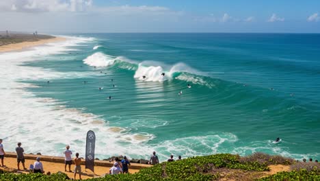 dynamic surfing scene captured from a scenic overlook, showcasing surfers riding waves and spectators enjoying the natural ocean environment